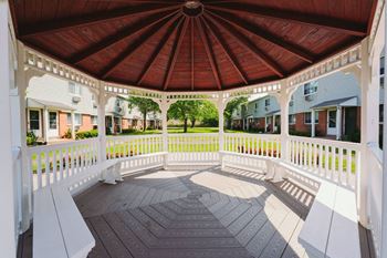 A gazebo with a wooden roof and white benches